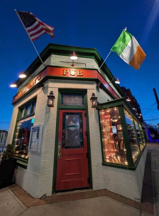 The corner entrance of O'Sullivan's Irish Pub at dusk, with American and Irish flags